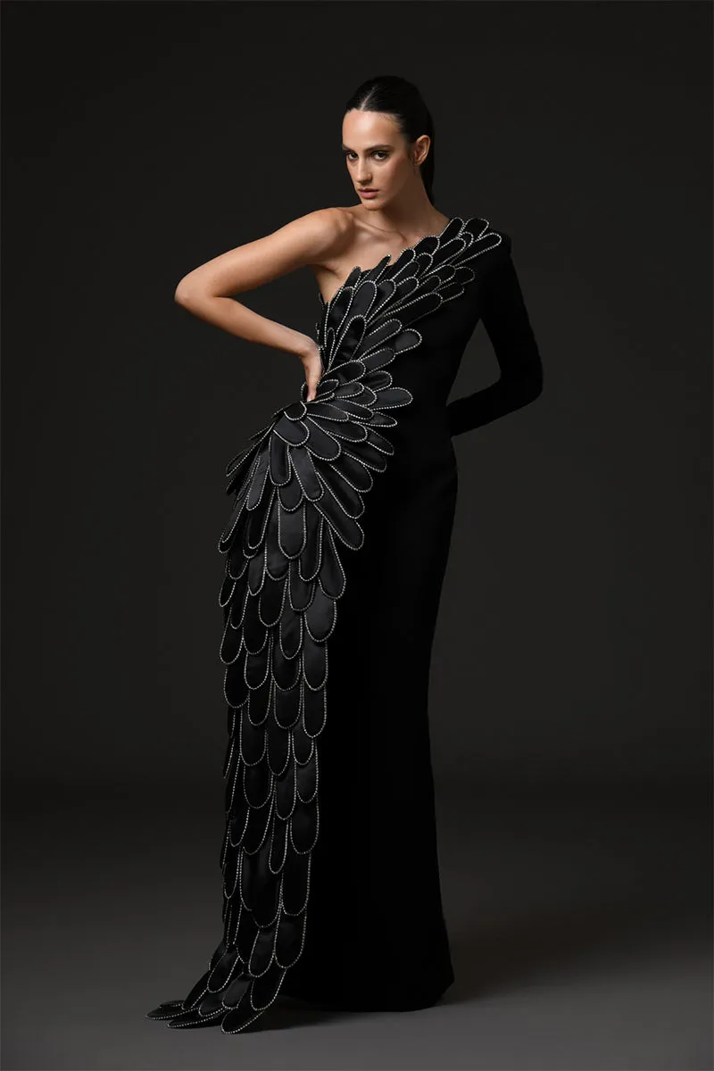 A sculpted gown in black silk crêpe paired with a winged cape of layered 3D hand-crafted plumes in scuba and crystals